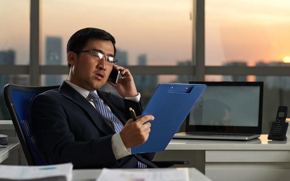 Man looking at clipboard while on the phone